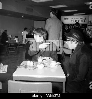 John Lennon und George Harrison von den Beatles-pop-Gruppe, Zigaretten rauchen und, die Getränke am Flughafen vor der Abreise nach Stockfoto