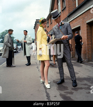 60er Jahre Mode der 1960er Jahre Kleidung Frau in gelb-Orange und grün gemustertes Kleid Mann in Hut und Schwänzen Stockfoto