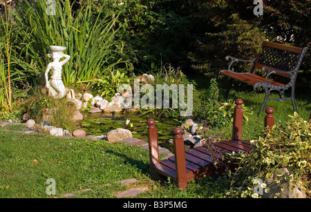 Garten mit Teich, Bank und kleine Holzbrücke. Stockfoto