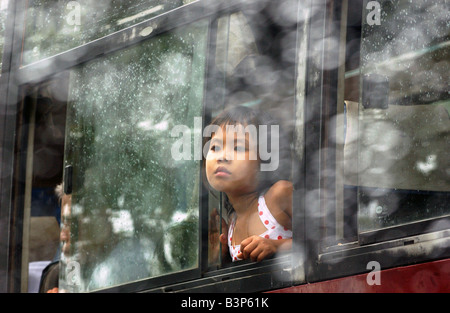Ein Mädchen schaut aus dem Fenster Regen durchnässt Bus warten auf die Fähre in Can Tho am Mekong-Delta durchqueren Stockfoto