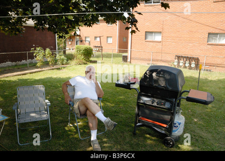 Mann sitzt im Hof mit grill Stockfoto