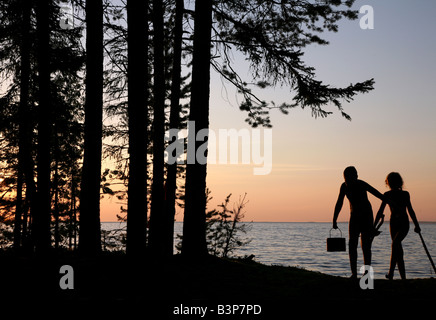 Kinder mit einem Wasserkocher und Brennholz zum Kochen über dem Lagerfeuer am Onega-See in Karelien, Russland Stockfoto