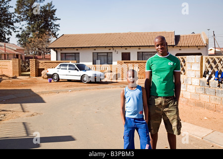 11MA-072 © Monkeyapple aFRIKA Sammlung großer Lager!  Vater und Sohn auf der Straße, Auto und Haus im Hintergrund stehend Stockfoto