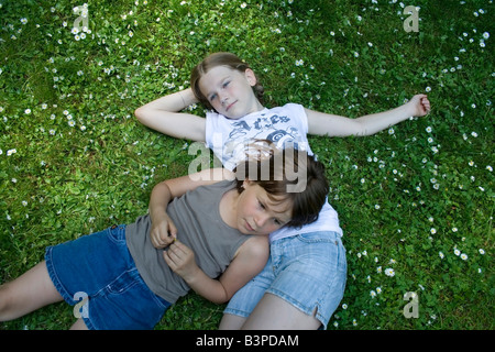 Zwei junge Mädchen im Grass liegen voller Gänseblümchen Stockfoto