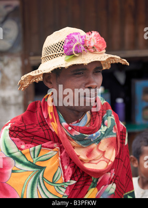 Madagaskar, Southern Highlands, Ambohimahasoa. Ein madagassischer Mann trägt einen lokal hergestellten Hut mit künstlichen Blumen geschmückt. Madagaskar ist bekannt für die außergewöhnliche Vielfalt und Stile ihrer lokalen Hüte, die von Region zu Region variieren. Verschiedene Fasern werden verwendet, um die Hüte je nach Verfügbarkeit zu weben; Dazu gehören Palmen (Bast, Badika, Manarana und Dara) oder Stroh. Stockfoto