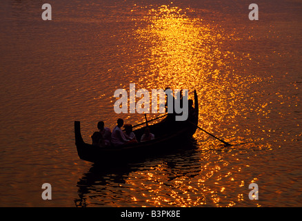 Myanmar. Ein Mann rudert eine lokale Holzboot über den Irrawaddy-Fluss bei Sonnenuntergang Stockfoto