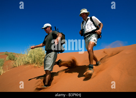 Männer zu Fuß hinunter Düne, Tok Tokkie Trail, NamibRand Nature Reserve, Namibia, Afrika Stockfoto