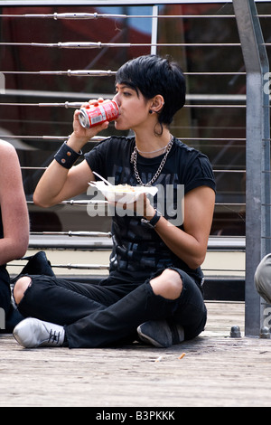 Camden Lock Market, isst sehr hübschen weiblichen Teenager in schwarz mit zerrissenen Jeans, Ketten und Lederarmband Snack von canal Stockfoto