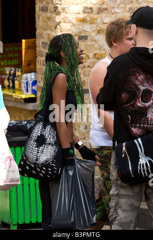 London, Camden Lock Market, Straßenszene, hübsch lächelnd schwarzes Mädchen, grüne Haarverlängerungen mit Freunden im gotischen Gang Stockfoto