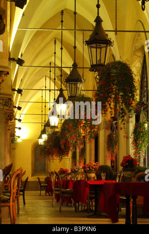 Verzierte Lampen hängen über dem Café-Tischen unter den Bögen der Tuchhallen (Sukiennice), Marktplatz, Krakau, Polen Stockfoto