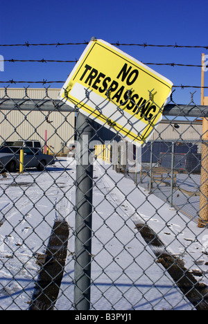 Eine alte "No Trespassing" Schild hängt schief an einen Stacheldrahtzaun. Stockfoto