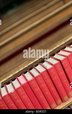 Roten Bibeln und Gesangbücher in Folge gegen Kirchenbänke in einer Kirche Stockfoto