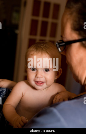 Mutter hält lächelnd acht Monate altes Babymädchen zu Hause Stockfoto