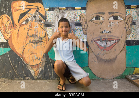 Ein brasilianischer junge posiert für die Kamera gegen Graffiti an der Wand bei einer Favela in Rio De Janeiro. Stockfoto