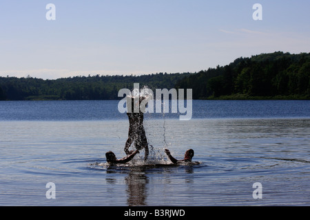 Deer Lake in Michigan USA drei Jungen Brüder Caucasian haben Spaß beim Spielen im Wasser springen horizontal in den USA US Hi-res Stockfoto