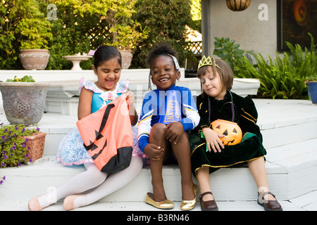 Kleines Mädchen gekleidet wie eine Ballerina, Cheerleader und Prinzessin zum Lachen und spielen während der Überprüfung ihre Leckereien. Stockfoto