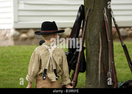 Ein Junge in der Nähe von Gewehre stützte sich auf einen Baum im Feldlager Civil War Reenactment Stockfoto