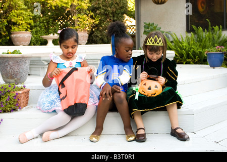 Kleine Mädchen verkleidet als Ballerina und Prinzessin ihre Halloween-Leckereien, überprüfen während die Cheerleader in der Prinzessin Tasche lugt Stockfoto