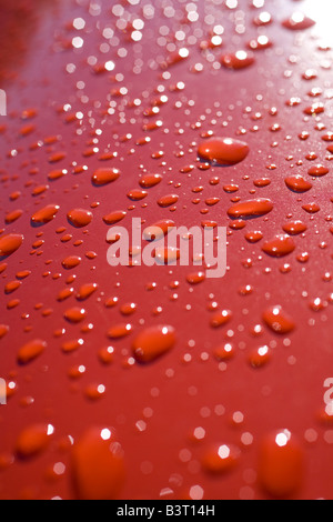 Wasser auf orange Auto nach Regen Stockfoto