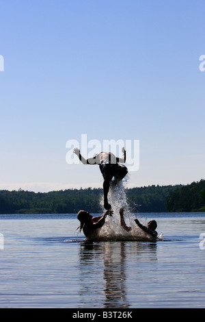 Deer Lake in Michigan USA drei Jungen Brüder Männer Kaukasier spielen Spaß im Wasser springen zu Wasser springen vertikal High-res Stockfoto