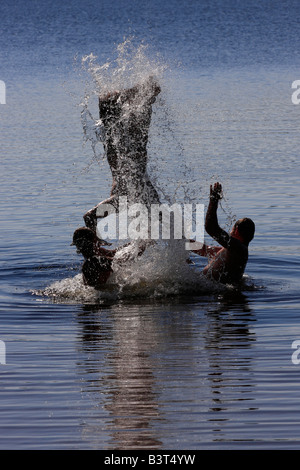 Deer Lake in Michigan USA drei Jungen Brüder Männer Kaukasier spielen Spaß im Wasser springen zu Wasser springen vertikal High-res Stockfoto