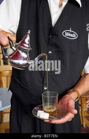 Marokko, Tanger. Ein Kellner schenkt ein Glas Pfefferminztee, Marokkos Lieblingsgetränk. Stockfoto