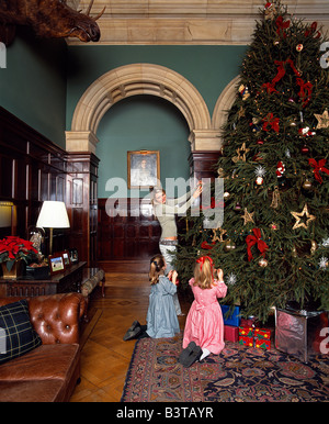 England, Leicestershire, Stapleford. Kinder schmücken den Weihnachtsbaum im Stapleford Park Country House hotel Stockfoto