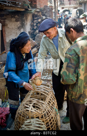 Asien, China, Yunnan Provinz, Yuanyang. Hani Frauen und Männer tauschen über Huhn auf Shengcun Dorfmarkt. Stockfoto