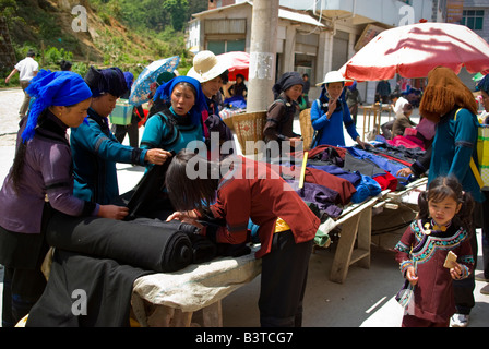 Asien, China, Yunnan Provinz, Yuanyang. Hani Frauen suchen aus Stoff auf dem Dorfmarkt Shengcun. Stockfoto