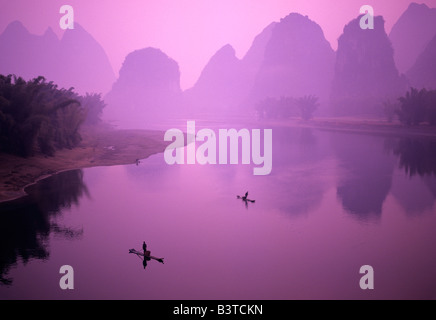 Asien, China, Guanxi, Yangshou. Fischer auf Floß in Li-Fluss. Stockfoto