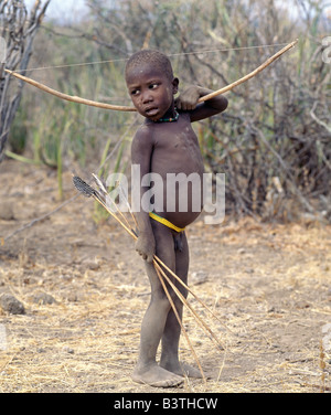 Tansania, Arusha, Lake Eyasi. Ein Hadza junge trägt einen Bogen und Pfeile. Die Hadzabe sind eine 1000-Seelen-Gemeinde von Jägern und Sammlern, die in der Lake Eyasi-Becken seit Jahrhunderten gelebt haben. Sie sind einer von nur vier oder fünf Gesellschaften in der Welt, die immer noch in erster Linie von der Wildtiere Leben verdienen. Stockfoto