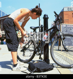 Eine weibliche Radfahrer ihr Fahrrad zu einem Hitching Post in Spitalfields in East London England KATHY DEWITT sperren Stockfoto