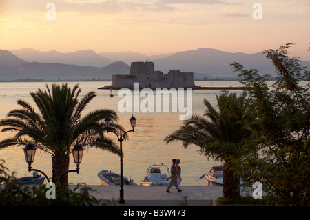Zwei Menschen laufen vor der Boote. Darüber hinaus ist das Wasser Burg Bourtzi. Eine venezianische Burg in der Mitte des Hafens von Nafplio entfernt. Stockfoto