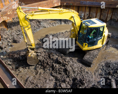 Ein kleiner Bagger bewegt Erde auf einer Baustelle. Stockfoto