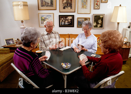 Vier ältere Freunde Spielkarten im Wohnzimmer einer Privatwohnung Stockfoto