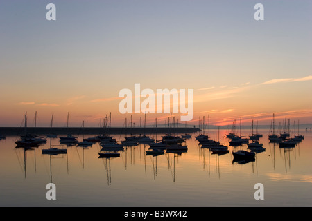 Silhouette Boote im Morgengrauen auf ruhiger See im Hafen von Holyhead, Anglesey, Wales. Stockfoto