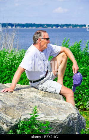 Ein Mann ruht auf einem Felsen am Strand Stockfoto