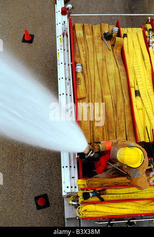 Draufsicht auf ein Feuerwehrmann auf ein Feuerwehrauto Besprühen mit Wasser aus dem Schlauch Stockfoto