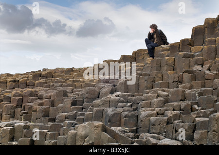 Man sitzt auf der Basaltsäulen. Giants Causeway, Nordirland Stockfoto