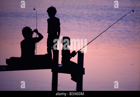 Mutter & Kinder Angeln von einem Pier an einem See bei Sonnenuntergang Stockfoto