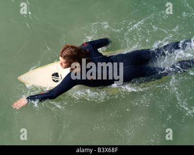 Surfer, die flach auf seinem Surfbrett paddeln in Richtung der Wellen, die von oben gesehen Stockfoto