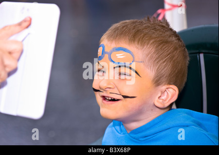 Junge nach seinem Gesicht sehen, Lächeln gemalt in Spiegel, Gesicht malen Ecke Acton Food Festival Acton W3 London Vereinigtes Königreich Stockfoto