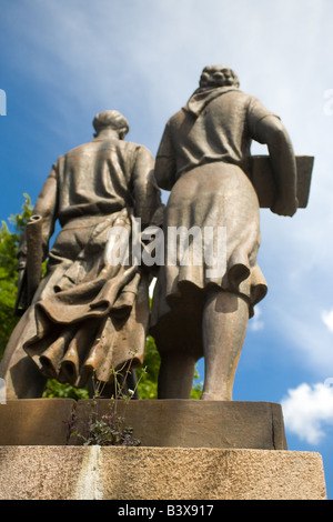 Unkraut sprießen hinter zwei Bronzeskulpturen Sozialrealismus mit Wolken am blauen Himmel in Vilnius Litauen über die Grüne Brücke. Stockfoto