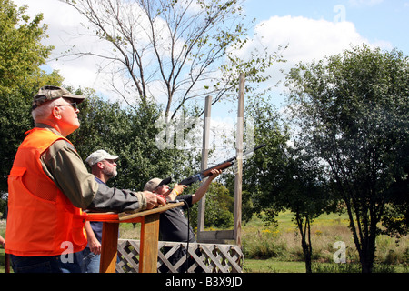 Ein Junge Shooter mit seinem Vater, mit dem Ziel eine Wurfscheibe bei einer Skeet Schießstand in Wisconsin. Ein Beamter hält die Ergebnisse. Stockfoto