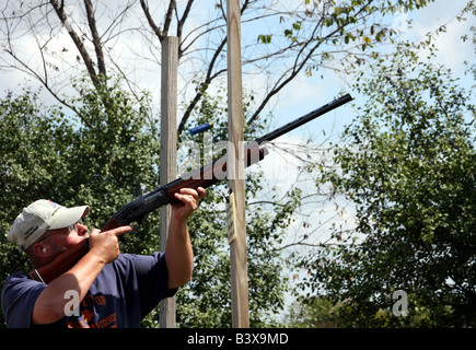 Eine männliche Schütze mit einem Gewehr, mit dem Ziel eine Wurfscheibe bei einer Skeet Schießstand in Wisconsin Stockfoto