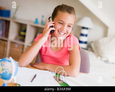 Junges Mädchen ihre Hausaufgaben, sprechen auf einem Handy ablenken Stockfoto