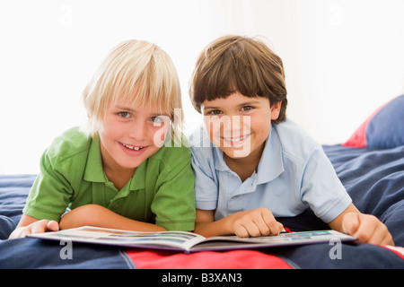 Zwei jungen, liegend auf einem Bett und las ein Buch Stockfoto