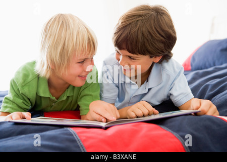 Zwei jungen, liegend auf einem Bett und las ein Buch Stockfoto