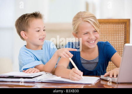 Junge zeigt auf Big Sisters Hausaufgaben auf Laptop Stockfoto