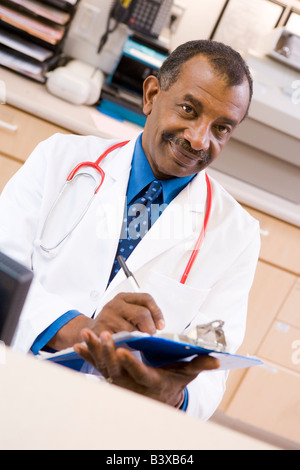 Ein Arzt schriftlich auf einem Klemmbrett an der Rezeption eines Krankenhauses Stockfoto